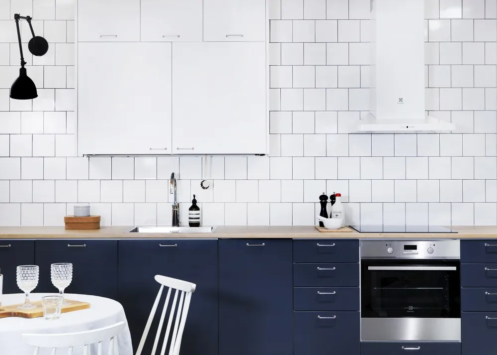 sinivalkoinen keittiö kromisilla lankavetimillä ja tammitasolla